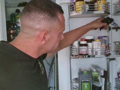 Professional pest control technician applying ant gel in a cupboard for infestation prevention